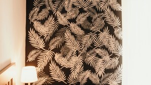 A room with a black wall featuring a white fern leaf pattern, a radiator, a lamp, and a bed with a red pillow. - Casa Boutique ALEGRÍA, aromas and art. (Caudete de las Fuentes)