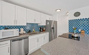 Una cucina moderna con mobili bianchi, un frigorifero in acciaio inossidabile, un forno a microonde ed una lavastoviglie.