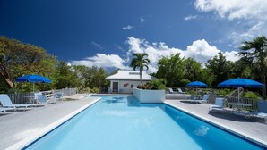 A swimming pool with lounge chairs and blue umbrellas, surrounded by trees and a building with a white roof. - Generator! 5 mins to Magens + 15 mins to STJ ferry (St Thomas)