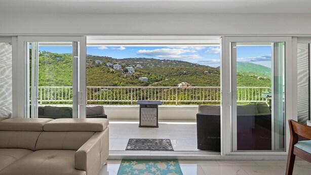 A balcony with a view of a green hillside and buildings, a sofa, a trash can, and a small table. - Generator! 5 mins to Magens + 15 mins to STJ ferry (St Thomas)