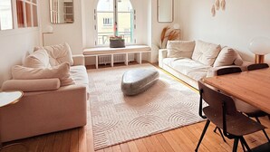 A modern living room with a sofa, a dining table, a stone accent, and a view through a large window. - Boho-chic cocoon in Neuilly-sur-Seine. (Neuilly-sur-Seine)