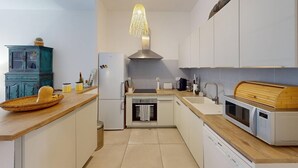 A modern kitchen with white cabinets, a wooden countertop, a built-in oven, a dishwasher, and a unique hanging light fixture. - Charming apartment for 4/6 people in Mimizan Plage (MIMIZAN)