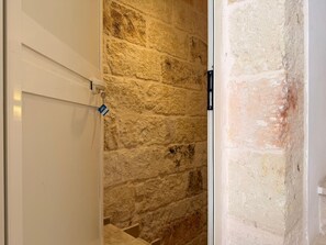 A room with a stone wall, a white door, and a black object on the wall. - Casa Antonia by Monholiday (Monopoli)