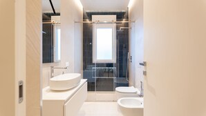 Un baño moderno con un espejo grande, dos lavamanos, una ducha y un inodoro.