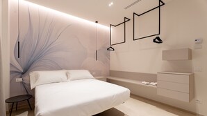 Un dormitorio moderno con una cama, una mesita de noche y un estante en la pared con toallas.