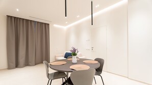 Un comedor moderno con una mesa redonda, sillas grises y un florero con flores.