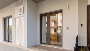 Un edificio moderno con amplios puertas correderas de vidrio, fachada blanca y un pequeño espacio exterior con escalones.