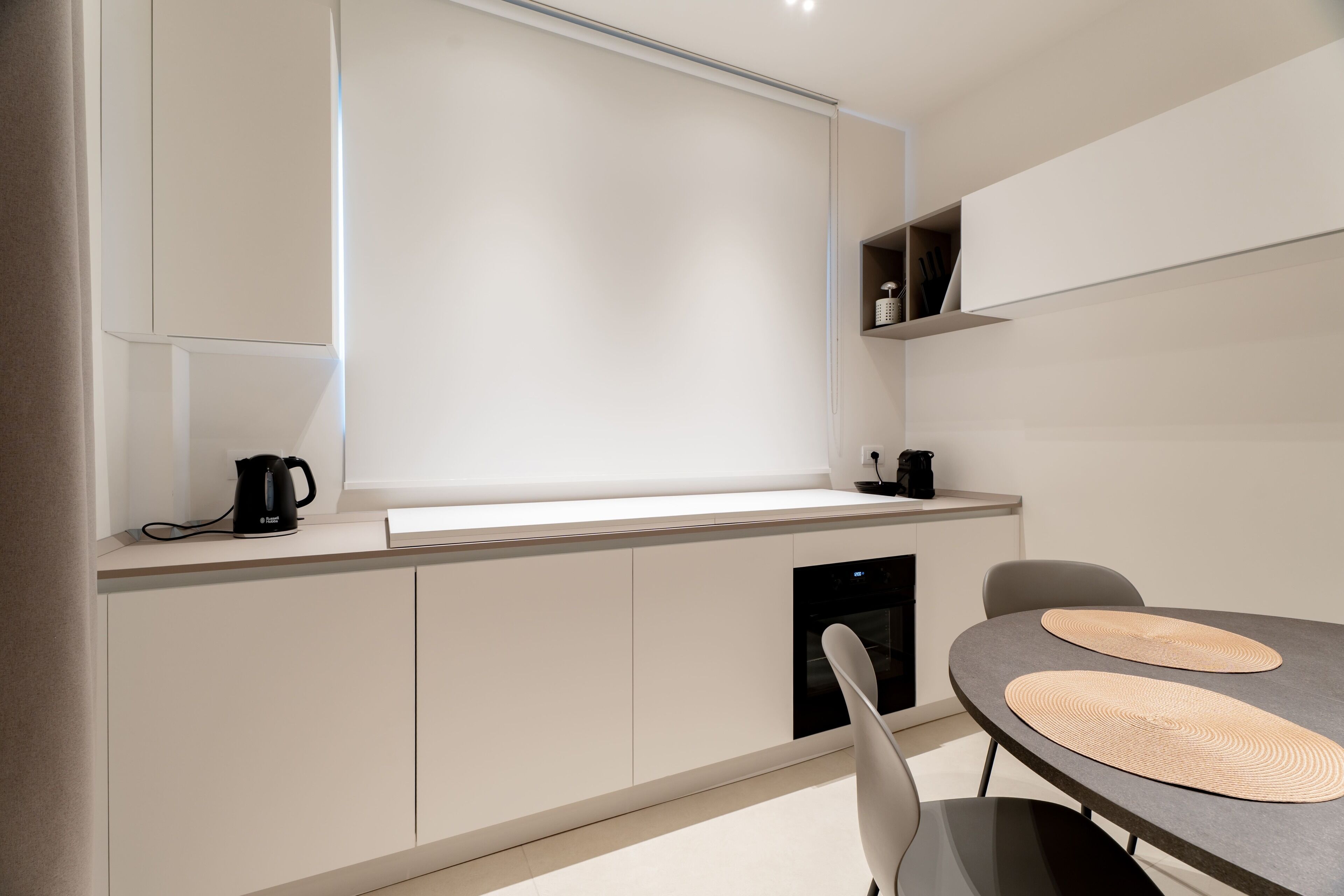 Una cucina moderna con forno integrato, macchina da caffè e zona pranzo con tavolo e sedie.