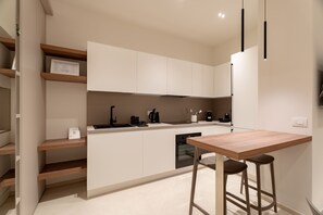 A modern kitchen with white cabinets, a wooden countertop, a built-in oven, and a bar stool. - Solymar Mare by Monholiday (Monopoli)