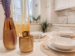 A dining table set with plates, bowls, glasses, and cutlery, with a vase and a smaller container on the table. - Flatsharing - Campanini Blue suite - 3 bedroom (Milan)
