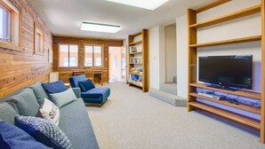 Una sala de estar acogedora con un sofá, un televisor y estanterías de madera.