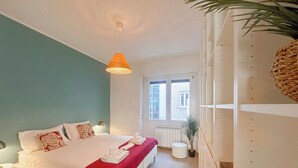 Una camera da letto con un letto, un comodino, una lampada, una finestra e una pianta in vaso.