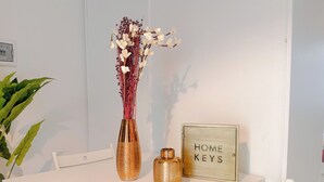 Un tavolo bianco con un vaso di fiori, una candela e un cartello che recita 'HOME KEYS'.