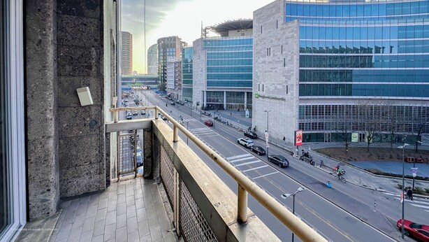 Un balcon avec vue sur la ville, un sol carrelé et une rambarde en métal.