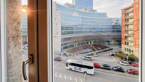 Un bâtiment moderne à la façade en verre, un autobus au premier plan et un ciel dégagé.