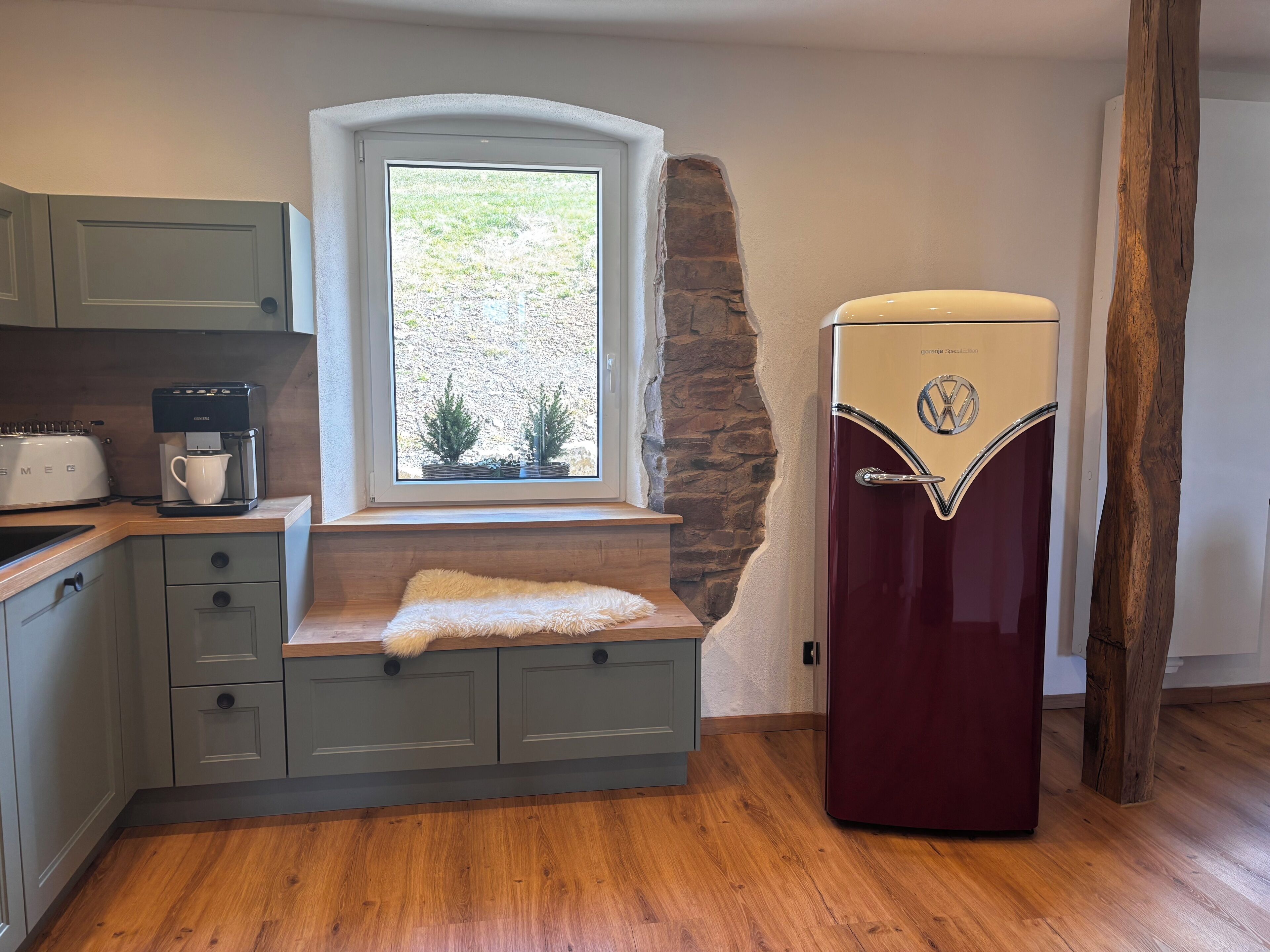 A kitchen with a built-in window, a vintage refrigerator, and a coffee maker.
