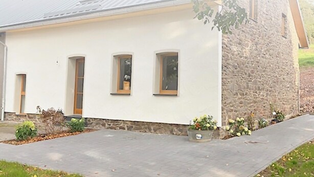 A building with a stone facade, a flat roof, and a paved entrance area with potted plants. - Renovated, beautifully furnished vacation home "Sannchen" with great attention to detail (Dahlem)