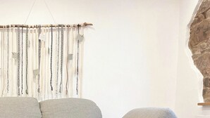 A modern living room with a grey sofa, a white round table with wooden legs, and a woven basket on the table. - Renovated, beautifully furnished vacation home "Sannchen" with great attention to detail (Dahlem)