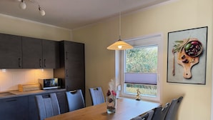 Eine moderne Küche mit dunklen Schränken, einem Holztisch und einem Fenster mit Blick auf Grünflächen.