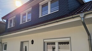 Ein zweistöckiges Haus mit Balkon, einer Tür und einem Fenster.