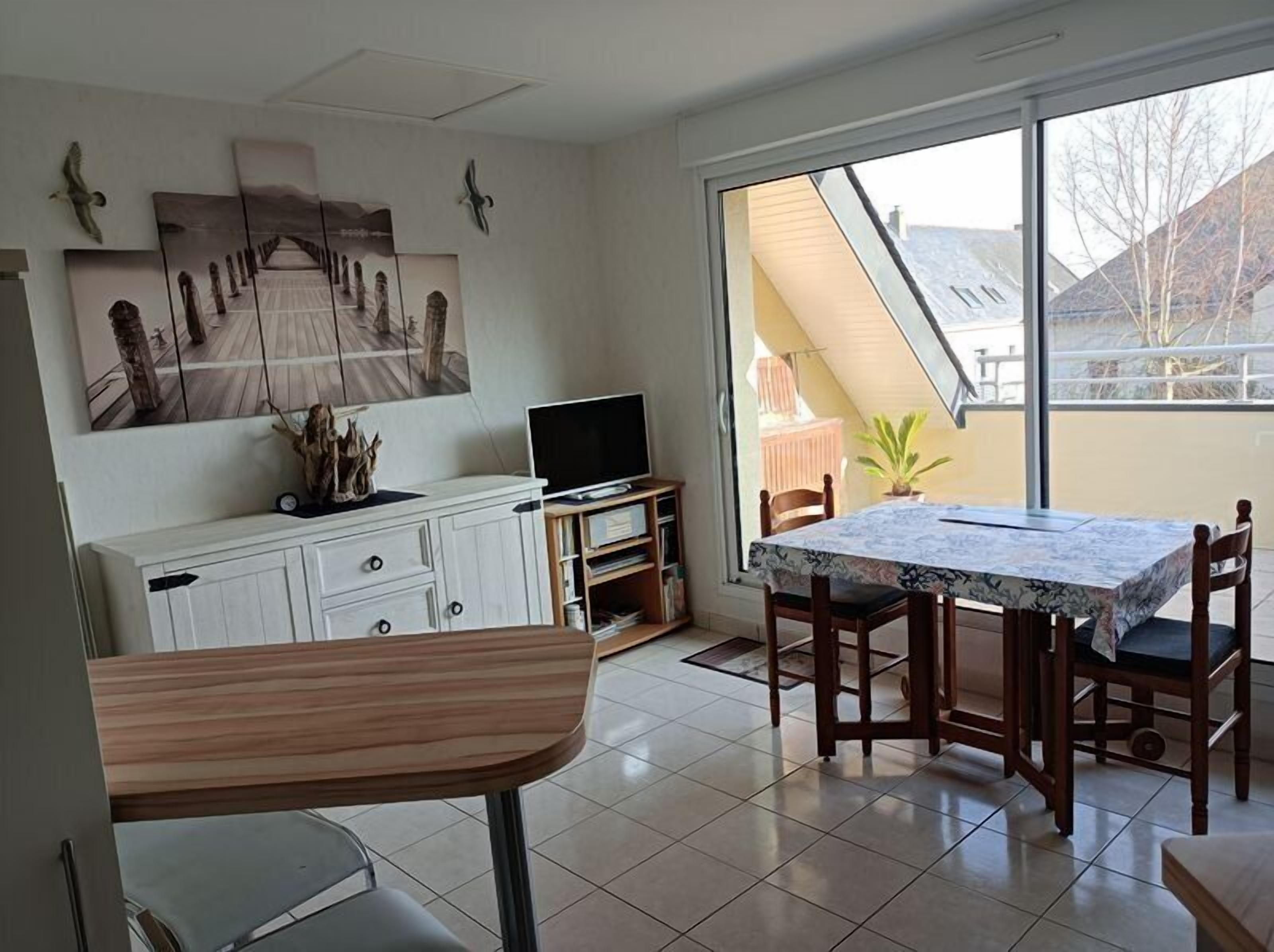 A dining area with a table and chairs, a television on a cabinet, and artwork on the wall.