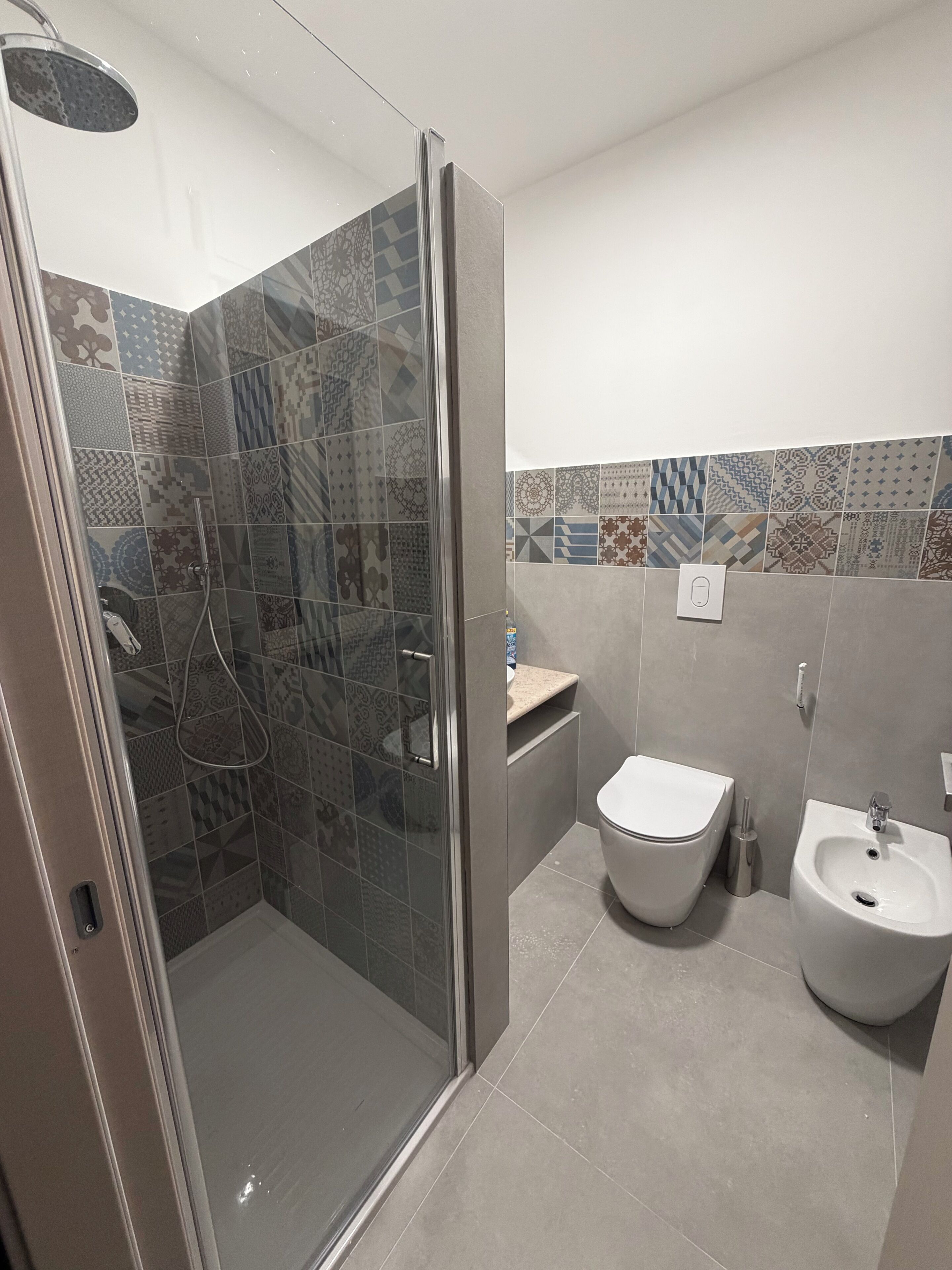 A bathroom with a glass-enclosed shower, a toilet, and a bidet.