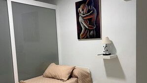 Ein Schlafzimmer mit Bett, einem Gemälde, einer Lampe und einer Klimaanlage.