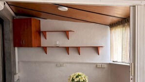 Eine kleine Küche mit einem Holztisch, weißen Stühlen und einer Blumenvase.