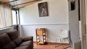 Ein Zimmer mit einem braunen Sofa, einem kleinen Holztisch und zwei weißen Stühlen.