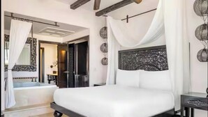 Ein Schlafzimmer mit einem großen Bett, einem Badezimmer mit einer Badewanne und einem Spiegel mit aufwendiger Rahmung.