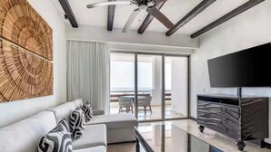Ein modernes Wohnzimmer mit einer Couch, einem Flachbildfernseher und Blick auf den Ozean.