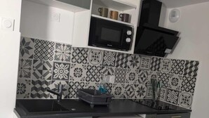 A compact kitchen with grey cabinets, a white refrigerator, a microwave, and patterned backsplash tiles. - Entire apartment - Angers, France (Angers)
