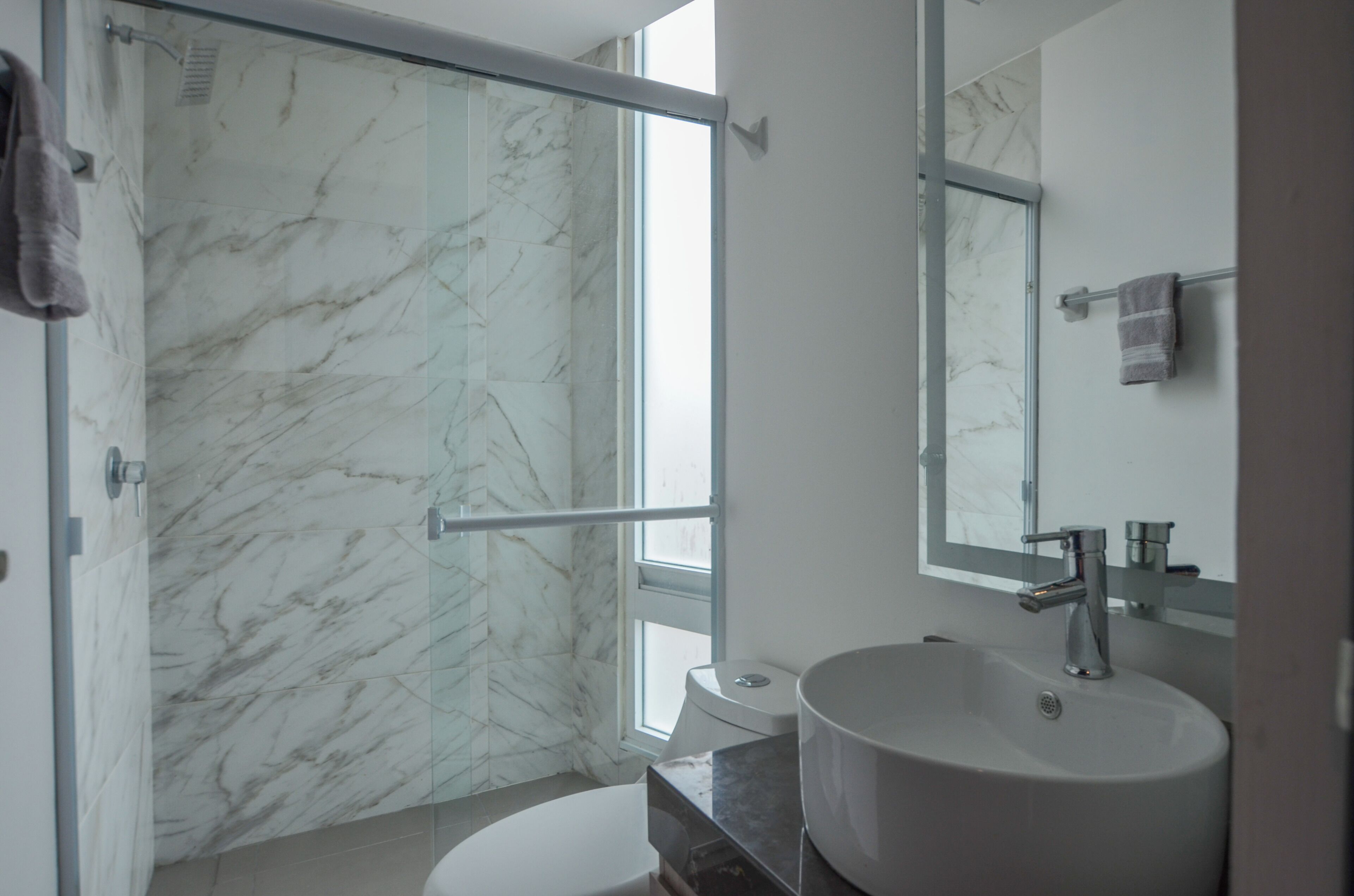 A bathroom with a glass shower enclosure, a sink, and a toilet.