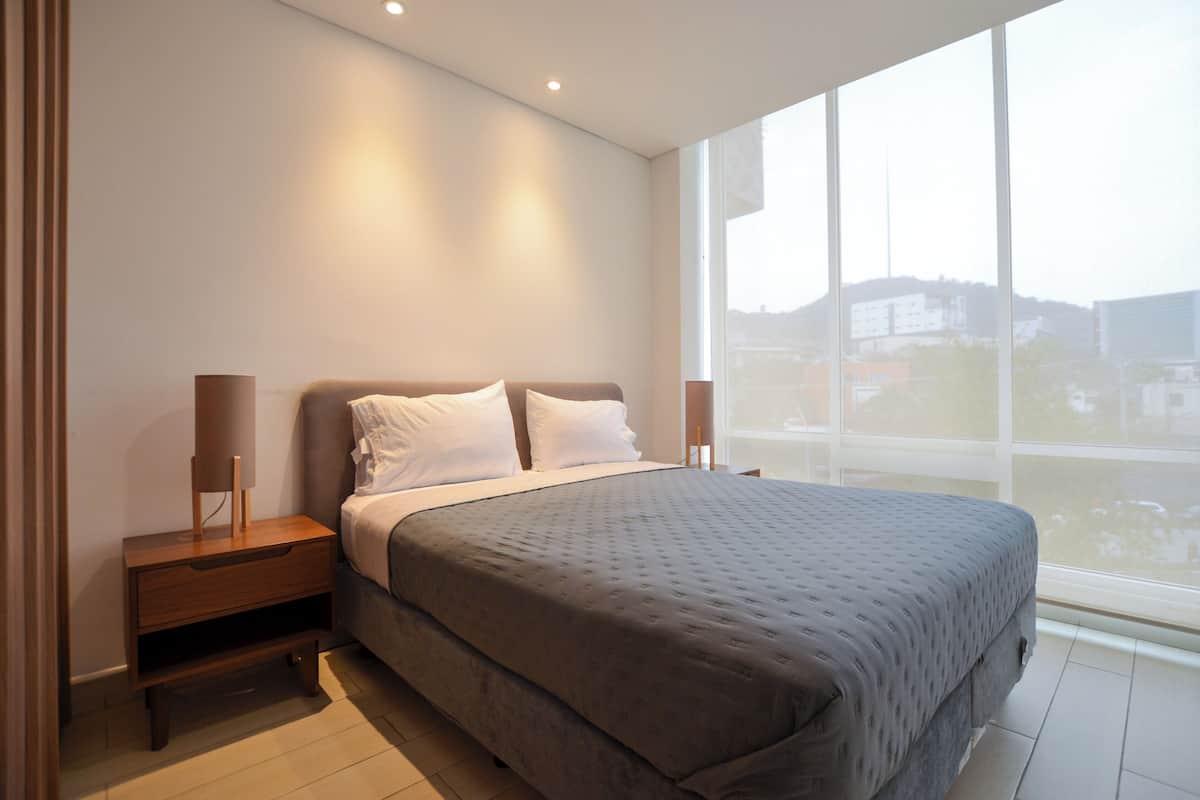 Una camera da letto con un letto grande, comodini e una finestra vista edifici.