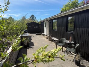 A patio area with a grill, outdoor seating, and a small shed. - Holiday idyll at Dejret Klit hot tub (Knebel)