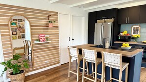 Eine moderne Küche mit einer Holzinsel, Barhocker, einem Kühlschrank und einer Mikrowelle.