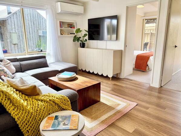 Un salon moderne avec un canapé, une table basse et un téléviseur.