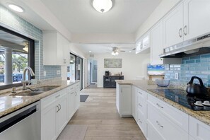 A modern kitchen with white cabinets, granite countertops, and a view of the outdoor area. - Punta Gorda Isles Vacation Home - Waterfront Home with Private Pool! (Punta Gorda)