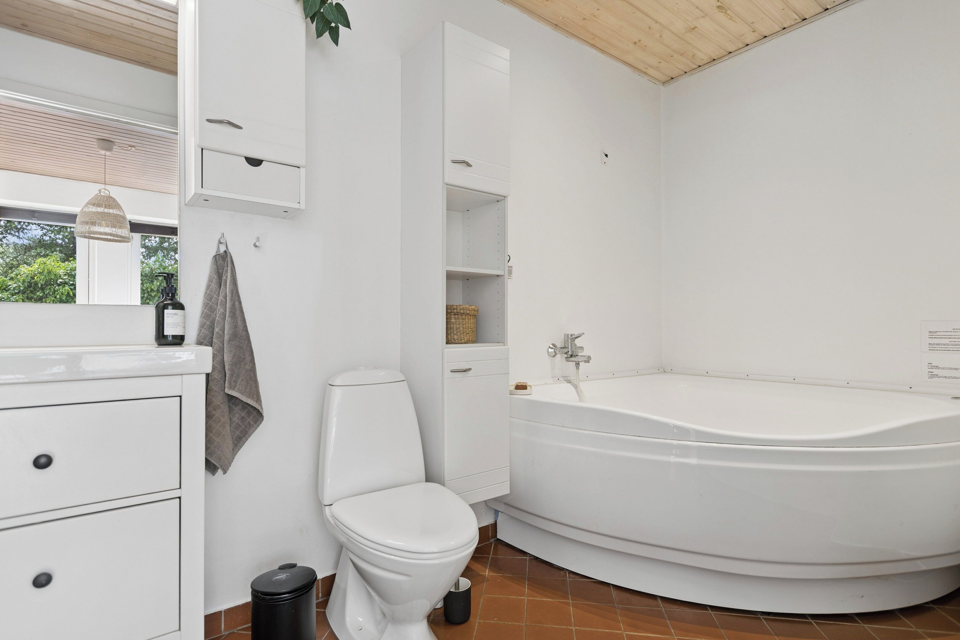 Bany amb vàter, un lavabo, un mirall, un suport per a tovalloles, una prestatgeria i una banyera.