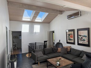 Ein modernes Wohnzimmer mit einer Eckcouch, einem Couchtisch und einer Treppe, die in eine obere Ebene führt.