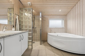 A bathroom with a shower, a bathtub, a sink, and a window.
