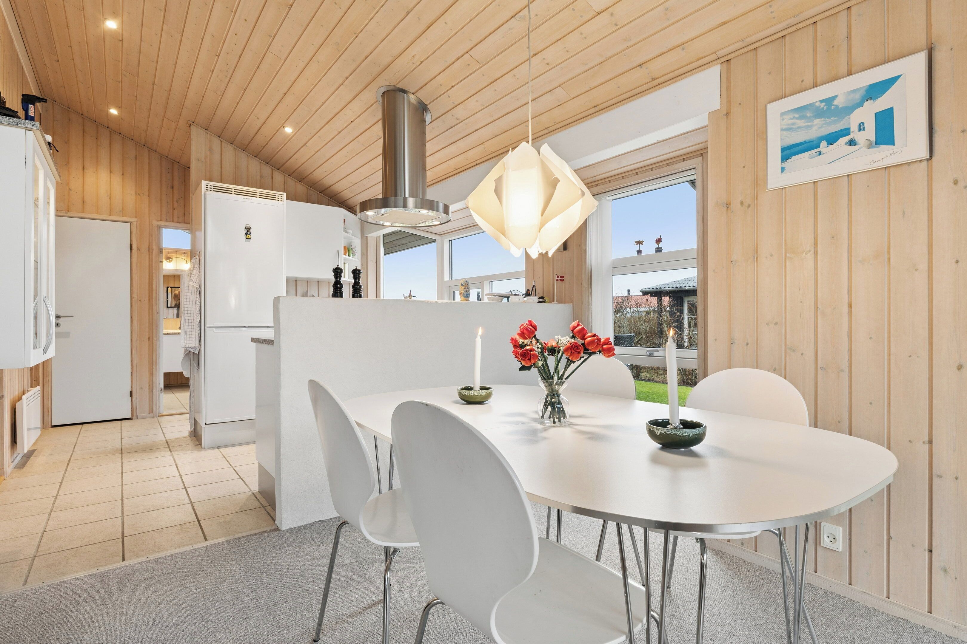 Una cucina moderna con elettrodomestici bianchi, una zona pranzo con tavolo e sedie bianche e un'ampia finestra.