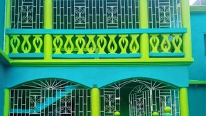 A two-story building with balconies, arched windows, and decorative metal railings. - Welcome to Grace Guest House. A peaceful and comfortable home. (St. Elizabeth Parish)