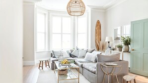 Un salon moderne avec un canapé, une table basse et un luminaire suspendu.