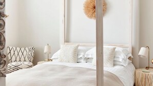 Un lit à baldaquin avec une couvre-lit blanche, un élément de décoration circulaire au mur et une table de chevet avec une lampe.