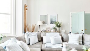 Un salon avec un canapé, une lampe, des tableaux encadrés et une porte.