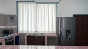 A kitchen with a stove, microwave, sink, and refrigerator. - Casa Cruz (Brisas de Zicatela)