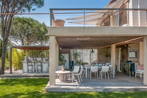 Eine überdachte Terrasse mit Essbereich, einer Bar und einer Pergola.