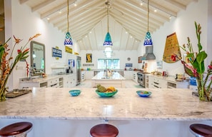 A spacious kitchen with a central island, pendant lights, and a high ceiling.