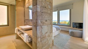 A modern bathroom with a stone accent wall, a large window, and a television. - Villa Marat - Four Bedroom Villa, Sleeps 8 (Astratigos)